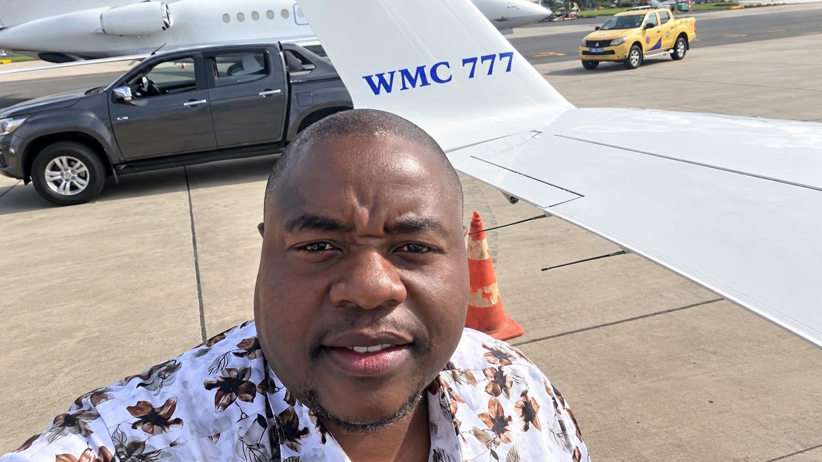 Wicknell Chivayo taking a selfie on an airport tarmac beside a small white aircraft marked ‘WMC 777’