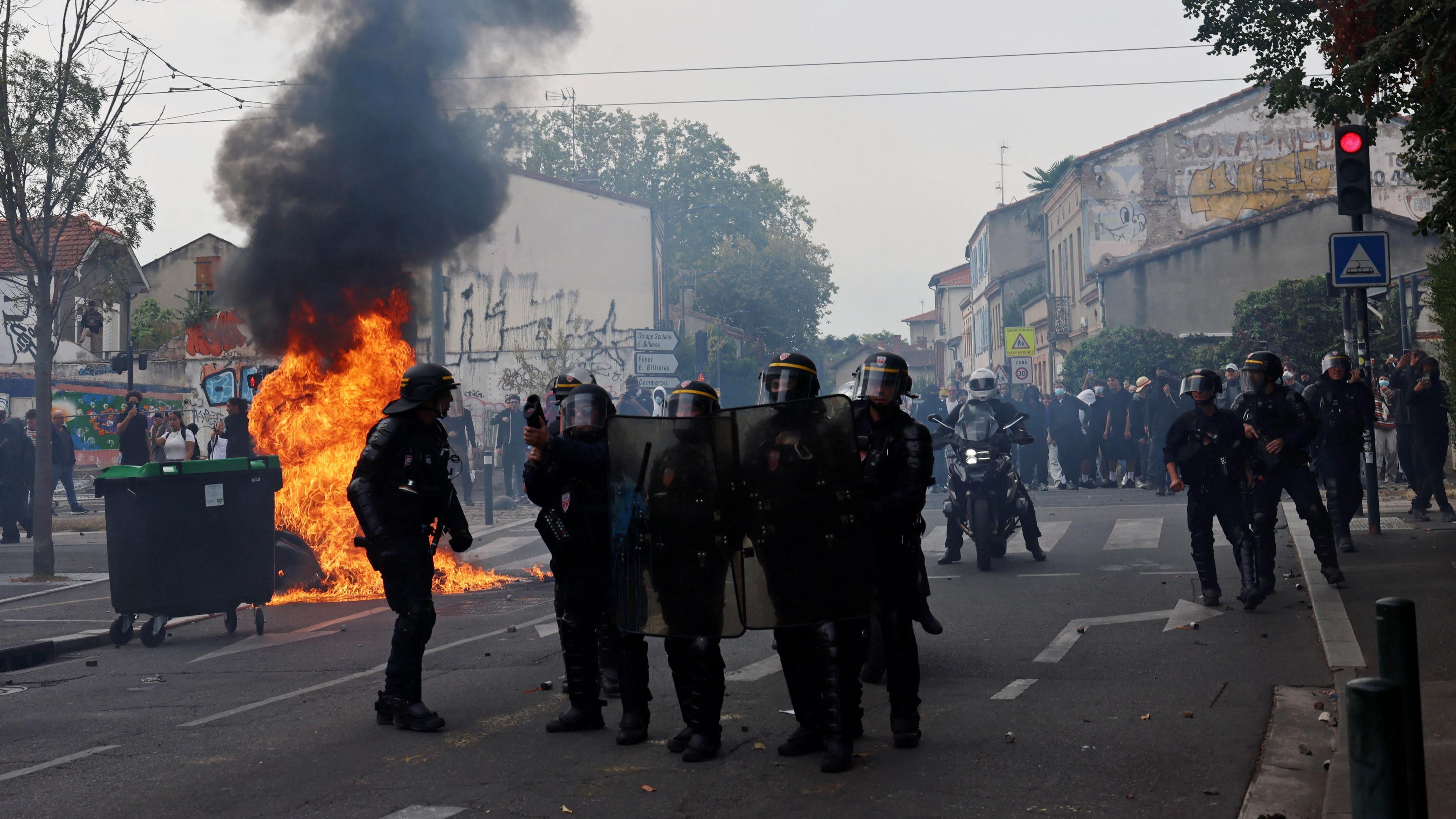 French riot police stand in position amid clashes during a protest by high school students outside the Lycee Deodat-de-Severac high school