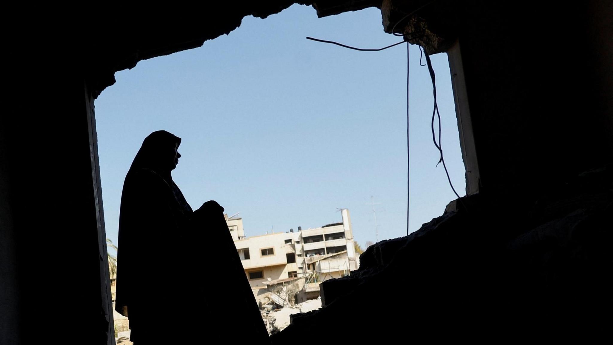Woman inspecting a damaged home in Gaza