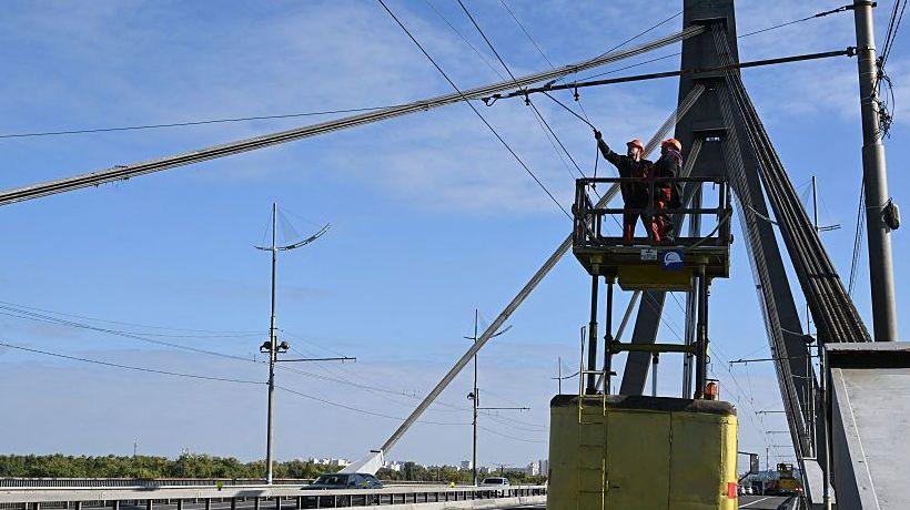 Technicians repair overhead trolleybus power lines that were damaged following an attack on the Pivnichnyi (Northern) Bridge in Kyiv